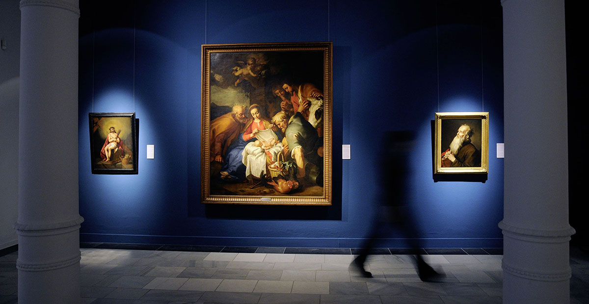 State Museum Schwerin: dark room with three lit paintings in front of a blue wall © nordlicht State Museum Schwerin: dark room with three lit paintings in front of a blue wall