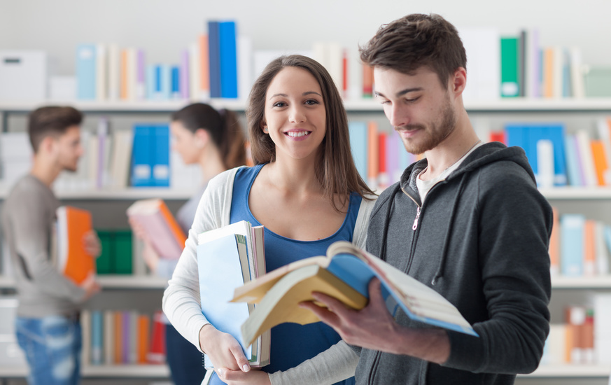 Students in a library holding books and studying together